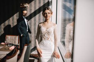 woman in white lace dress standing beside glass window