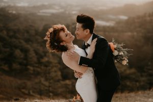 man in black suit kissing a woman in white dress