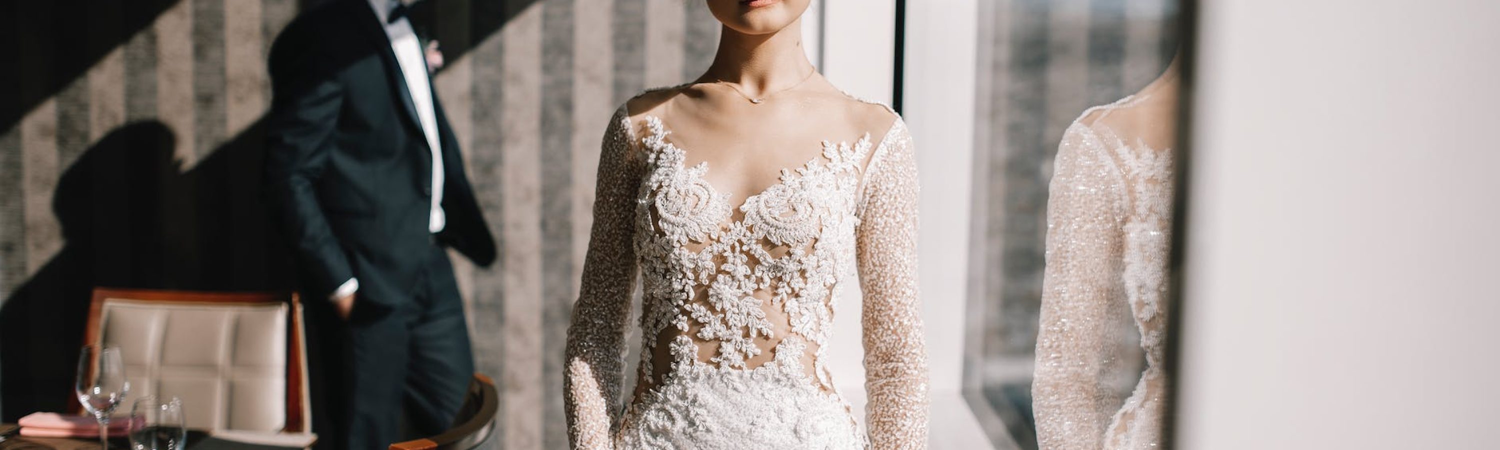 woman in white lace dress standing beside glass window